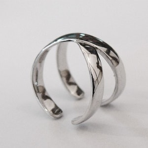 Puede incluir: Un anillo de plata con un diseño de doble banda. Las bandas están retorcidas y se cruzan.