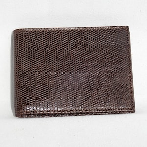 Puede incluir: Una cartera de cuero marrón con un patrón texturizado y estampado.