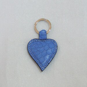 Peut inclure: Un porte-clés en cuir bleu en forme de cœur avec un anneau argenté.