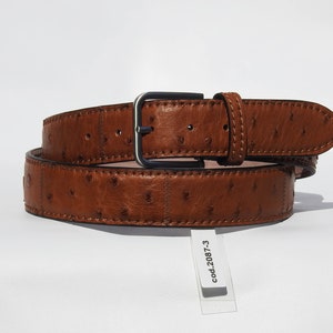 May include: A brown leather belt with an ostrich skin pattern and a silver buckle. The belt is rolled up and has a tag that says "cod.2087-3".