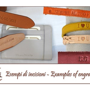 May include: Examples of leather engraving options, including a wallet, belt, bracelet, and a small piece of leather. The text on the items includes "14/02/2015", "www.cenci.com", "@...SEMPRE AL TUO FIANCO", "I &hearts; U", and "E.G."