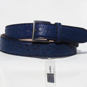 May include: A dark blue leather belt with a silver buckle and an ostrich skin pattern. The belt is rolled up and has a tag attached that says "cod. 2087-6".