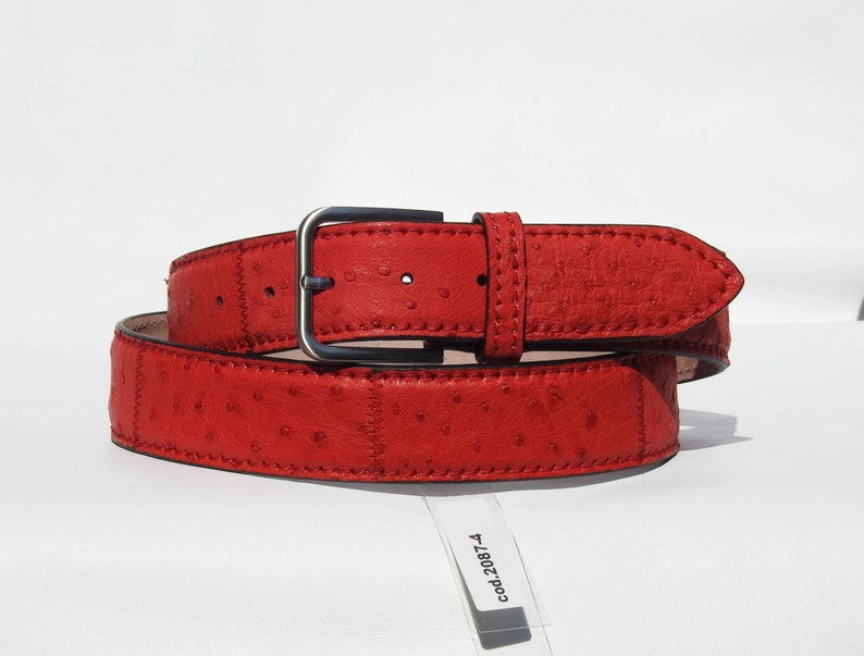 May include: A red ostrich leather belt with a silver buckle. The belt is stitched with red thread and has a tag that reads "cod.2087-4".