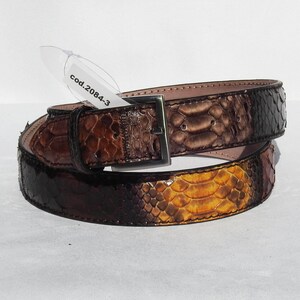 May include: A brown leather belt with a snakeskin pattern. The belt has a silver buckle and a tag that says "cod.20843".