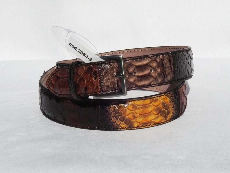 May include: A brown leather belt with a snakeskin pattern. The belt has a silver buckle and a tag that says "cod.20843".