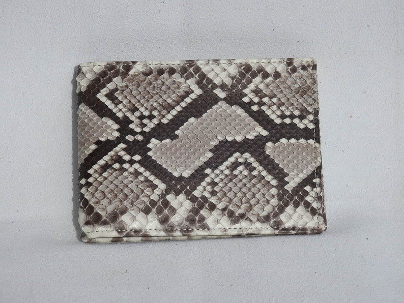 May include: A brown and white snakeskin wallet with a stitched edge.