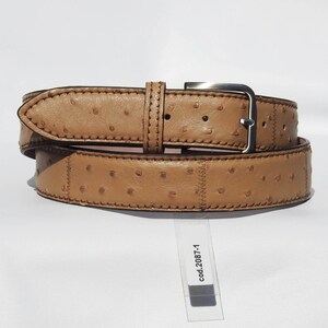 May include: A tan leather belt with an ostrich skin pattern and a silver buckle. The belt is folded in half and the tag reads "cod.2087-1".