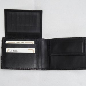 May include: A black leather wallet with multiple card slots and a billfold. The wallet is open and shows two credit cards with the text "CREDIT CARD" and "c 104" visible.