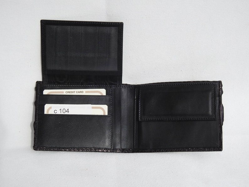 May include: A black leather wallet with multiple card slots and a billfold. The wallet is open and shows two credit cards with the text "CREDIT CARD" and "c 104" visible.