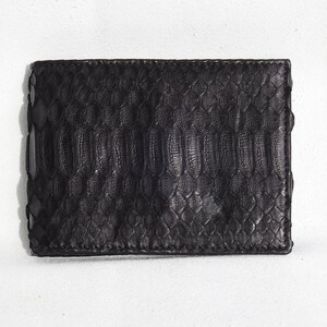 May include: A black leather wallet with a snakeskin pattern.