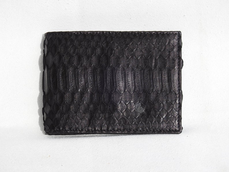May include: A black leather wallet with a snakeskin pattern.