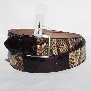 May include: A brown and beige snakeskin belt with a silver buckle. The tag attached to the belt reads "cod.20844".