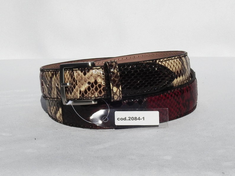 May include: A brown, black and red snakeskin belt with a silver buckle. The belt has a tag that reads "cod.2084-1".