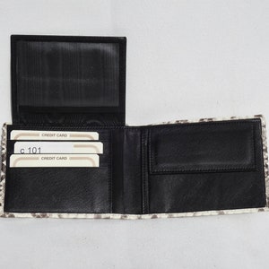 May include: A black leather wallet with a white and gray snakeskin pattern. The wallet is open and shows multiple card slots and a billfold. The text "CREDIT CARD" is visible on the card slots.