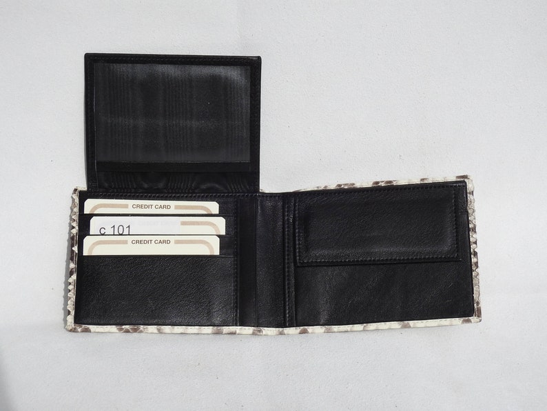 May include: A black leather wallet with a white and gray snakeskin pattern. The wallet is open and shows multiple card slots and a billfold. The text "CREDIT CARD" is visible on the card slots.