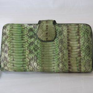 May include: A green snakeskin wallet with a zipper closure. The wallet has a flap closure with a decorative button.