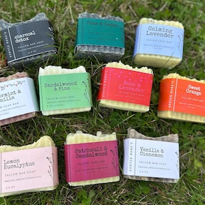 May include: A collection of nine tallow bar soaps with various scents, each wrapped with a label. Scents include Charcoal Detox, Pine & Cedar, Calming Lavender, Peppermint & Vanilla, Sandalwood & Pine, Rose & Lavender, Sweet Orange, Lemon Eucalyptus, Patchouli & Sandalwood, and Vanilla & Cinnamon.