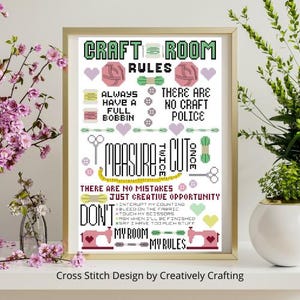 Könnte beinhalten: Ein gerahmtes Kreuzstichmuster mit dem Titel Craft Room Rules, das Text und Symbole von Garn, Spulen, Scheren, einem Maßband und Nähmaschinen zeigt. Das Design verwendet schwarzes, rosa, grünes, gelbes und violettes Garn auf weißem Grund.