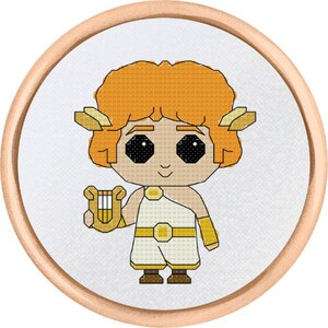 Op de afbeelding: Een kruissteek borduurring met een cartoonillustratie van een persoon met oranje haar die een lier vasthoudt. De persoon draagt ​​een witte tuniek met een gouden riem en gouden armbanden.