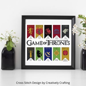 Puede incluir: Un diseño de punto de cruz enmarcado en negro que presenta los sellos de las Grandes Casas de Westeros de la serie de televisión Game of Thrones. Los sellos están dispuestos en dos filas de seis, con las palabras "Game of Thrones" en letras grandes debajo de la fila superior.