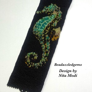 May include: Black beaded bracelet featuring a seahorse design in shades of teal, green, and gold. The bracelet has a decorative clasp and the text "Beadazzledgems Design by Nita Modi".