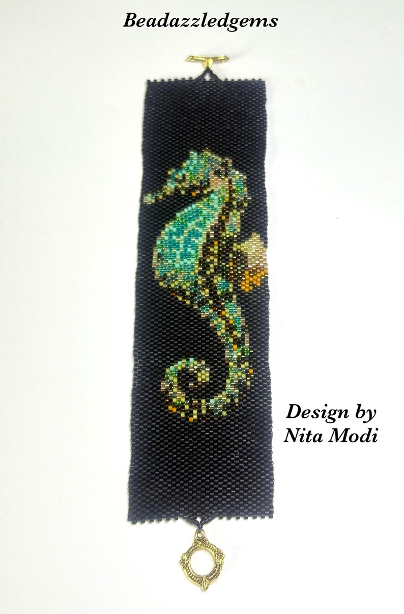 May include: Black beaded bracelet featuring a seahorse design in shades of teal, green, and gold. The bracelet has a gold-tone clasp and a decorative charm. Text on the image reads "Beadazzledgems" and "Design by Nita Modi."