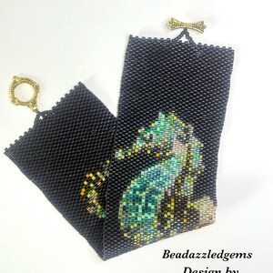 May include: Black beaded bracelet featuring a seahorse design in shades of teal, green, and gold. The bracelet has a gold-tone clasp and a decorative gold bow detail. The text "Beadazzledgems Design by Nita Modi" is visible.
