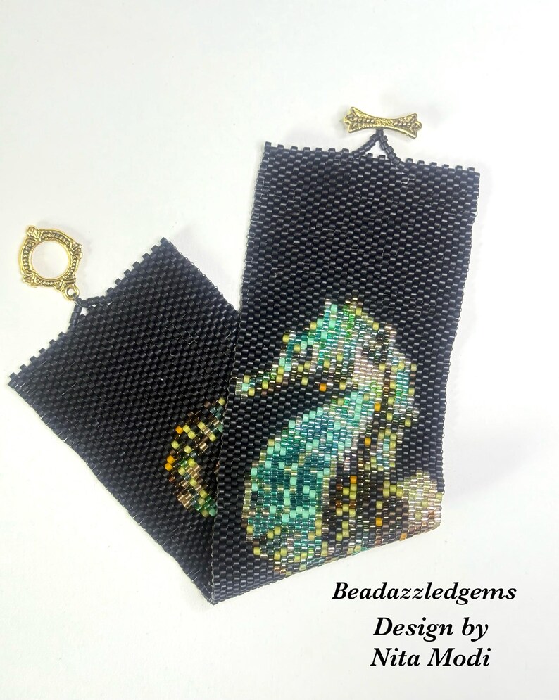 May include: Black beaded bracelet featuring a seahorse design in shades of teal, green, and gold. The bracelet has a gold-tone clasp and a decorative gold bow detail. The text "Beadazzledgems Design by Nita Modi" is visible.