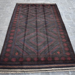Può includere: Tappeto rettangolare con sfondo grigio scuro e motivo geometrico a rombi rossi e blu. Il bordo presenta un motivo floreale ripetuto in rosso. Il tappeto ha un bordo sfrangiato.
