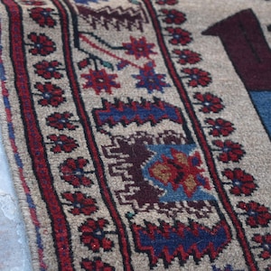 May include: A beige rug with a red, blue, and brown geometric pattern. The rug has a fringe border.