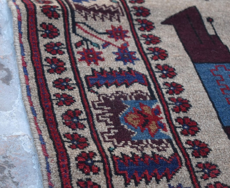 May include: A beige rug with a red, blue, and brown geometric pattern. The rug has a fringe border.
