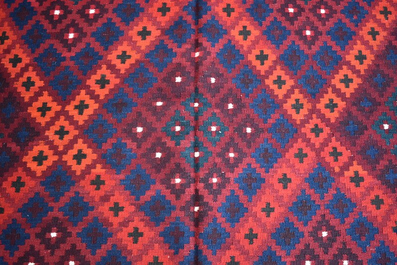 May include: A red, blue, and black patterned rug with a geometric design. The rug has a repeating pattern of squares and diamonds.