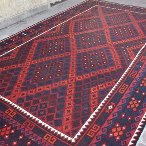 May include: A traditional red, black, and white patterned rug with a geometric design. The rug has a white border with a black and white geometric pattern.