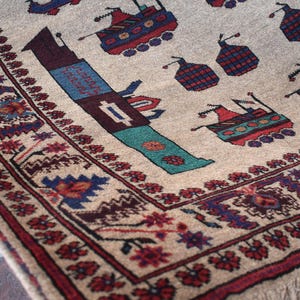 May include: A beige rug with a colorful geometric pattern. The rug features a repeating design of stylized ships and flowers. The rug has a fringe border.