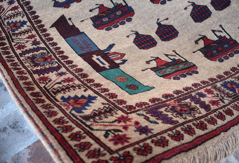 May include: A beige rug with a colorful geometric pattern. The rug features a repeating design of stylized ships and flowers. The rug has a fringe border.