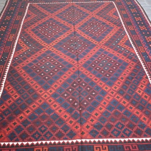 May include: A traditional red, blue, and white patterned rug with a geometric design. The rug has a white border with a black and white geometric pattern.