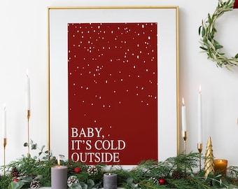 Könnte beinhalten: Ein gerahmter Druck mit rotem Hintergrund und weißen Schneeflocken. Der Text "BABY, IT'S COLD OUTSIDE" ist in Weiß auf dem roten Hintergrund gedruckt.