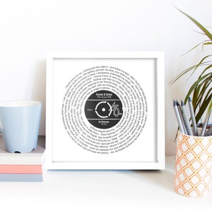 May include: A white framed print with a black and white circular design featuring the lyrics to the song "Perfect" by Ed Sheeran. The design includes the song title, artist name, and a record-style label with the number 45 and the date "25th January 2018". The text "Steven & Emma" is also included in the design.