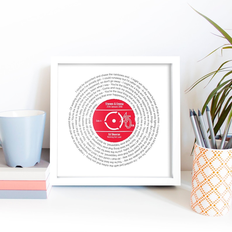 May include: A white framed print with a red vinyl record design. The record features the lyrics to the song "Thinking Out Loud" by Ed Sheeran. The record also includes the text "Steven & Emma 25th January 2018" and "Side A 45".