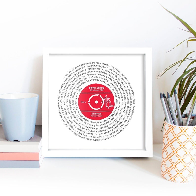 May include: A white framed print with a red vinyl record design. The record features the lyrics to the song "Thinking Out Loud" by Ed Sheeran. The record is labeled with the names "Steven & Emma" and the date "25th January 2018".