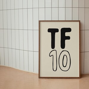 Pode incluir: Uma impress&atilde;o emoldurada com texto preto em fundo branco. O texto diz "TF 10".