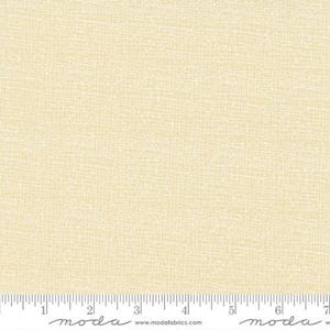 May include: Cream-colored fabric with a subtle, textured grid pattern. The fabric has a soft, off-white base with a delicate, lighter-colored overlay, creating a visual texture. A ruler is at the bottom of the image, with measurements in inches.