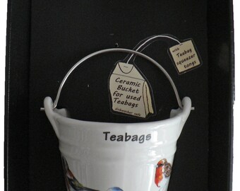 May include: White ceramic teabag bucket with a metal handle. The bucket has a bird design and the text "Teabags" printed on the front. The bucket comes with a teabag squeezer tongs.