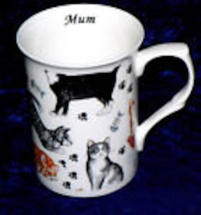 May include: White ceramic mug with a black handle. The mug has a design of various cats in black, white, gray, and orange. The word "Mum" is printed on the top of the mug.