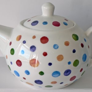 May include: White ceramic teapot with a lid, decorated with colourful polka dots in shades of red, orange, yellow, green, blue, and purple.