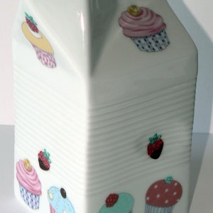 Milk carton shaped jug off white ceramic decorated with colourful cupcakes