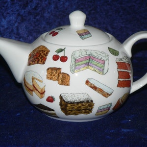 May include: White ceramic teapot with a handle and lid. The teapot is decorated with a colourful pattern of various cakes and pastries.
