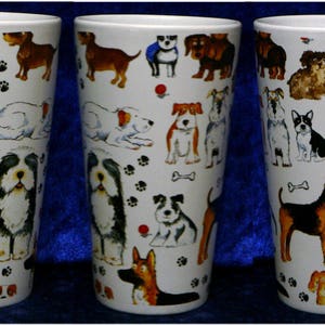 May include: Three white ceramic mugs with a tall, slender design. Each mug features a different pattern of colorful cartoon dogs with various breeds and poses. The mugs have a black handle and are perfect for coffee, tea, or hot chocolate.
