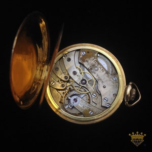 K&ouml;nnte beinhalten: Eine goldene Taschenuhr mit offenem Zifferblatt, das die komplizierten inneren Mechanismen des Uhrwerks freilegt. Das Zifferblatt der Uhr ist mit "Tiffany & Co. New York" beschriftet.