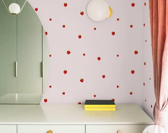 May include: A pale pink wall decorated with red strawberry stickers. A white dresser with wooden knobs is in the foreground, and a yellow and black box sits on top. A round white light fixture is mounted on the wall. The word "luvette's" is in the bottom right corner.